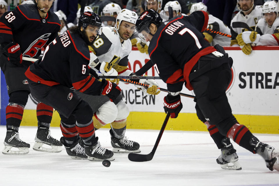 Vegas Golden Knights' William Carrier (28) loses control of the puck when confronted by the pairing of Carolina Hurricanes' Jalen Chatfield (5) and Dmitry Orlov (7) during the first period of an NHL hockey game in Raleigh, N.C., Tuesday, Dec. 19, 2023. (AP Photo/Karl B DeBlaker)