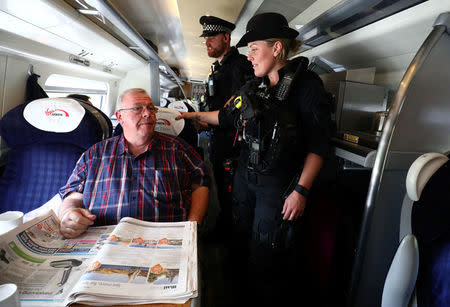 Armed police officers walk along the aisle of a train at Milton Keynes station, Britain May 25, 2017. REUTERS/Neil Hall