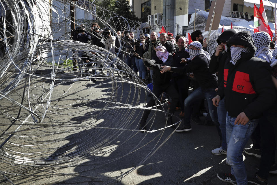 Protesters try to remove barbed wires that block a road leading to the U.S. embassy during a protest is held against the proposed peace deal for the Middle East by President Donald Trump, in Aukar, east of Beirut, Lebanon, Sunday, Feb. 2, 2020. Hundreds of Lebanese and Palestinians demonstrated Sunday near the U.S. embassy in Lebanon in rejection to a White House plan for ending the Israeli-Palestinian conflict. (AP Photo/Hassan Ammar)