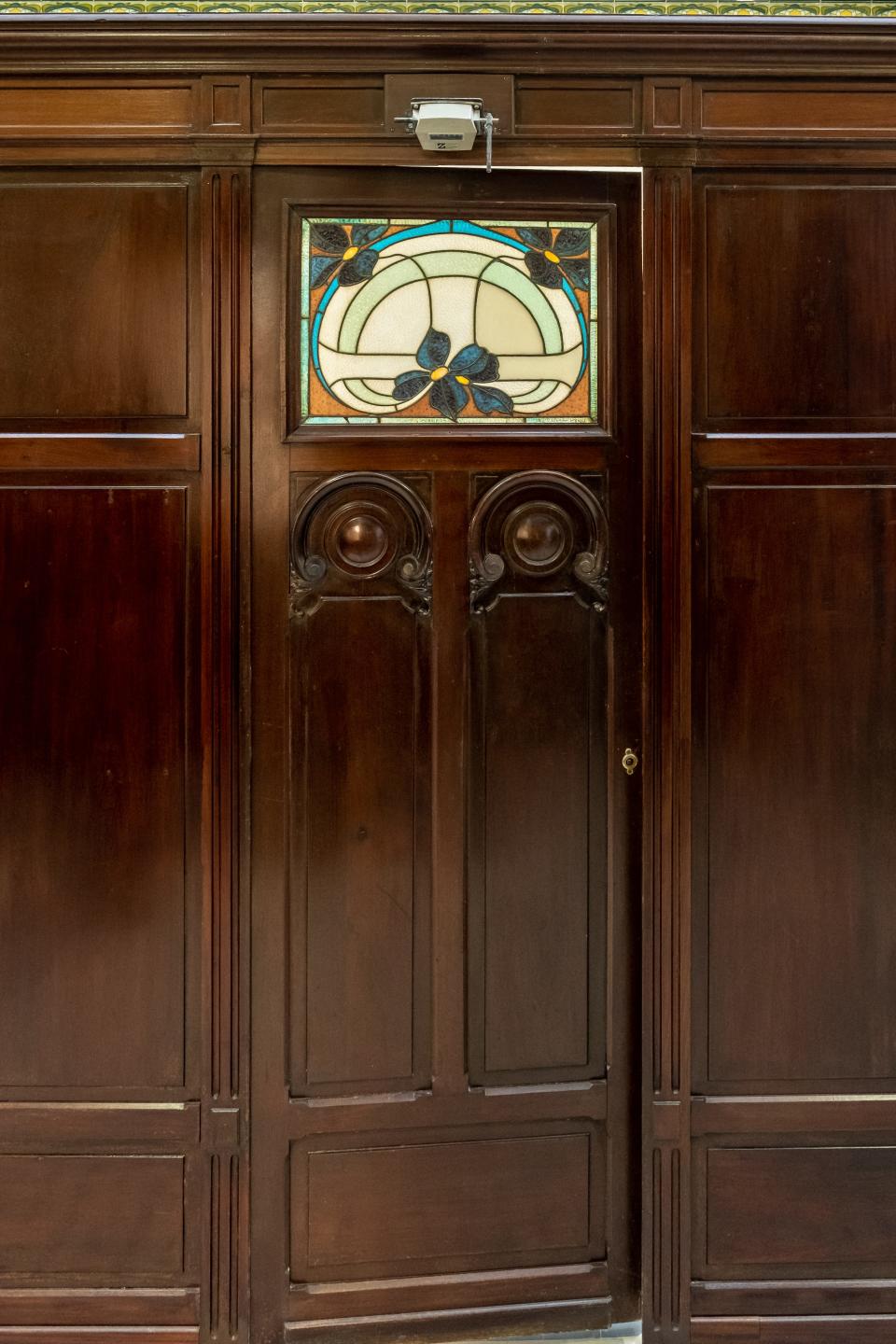 A mahogany door featuring a stained glass window in green, blue, and orange hues
