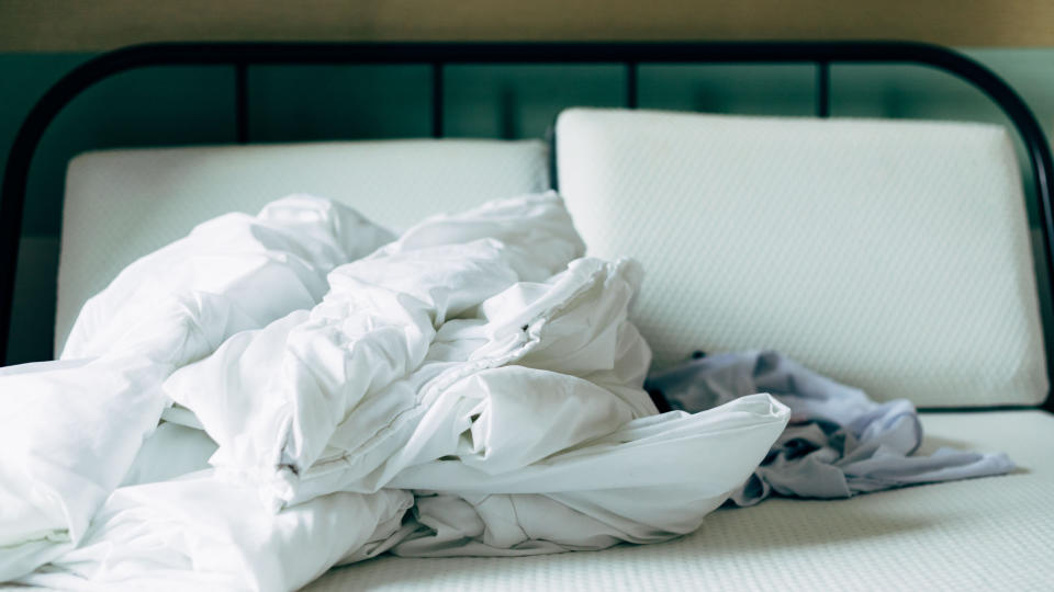 A mattress protector and sheets stripped off a bed before washing in the machine