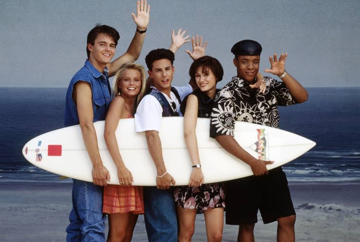 the cast holdlng a surfboard