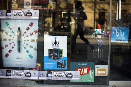 A woman runs past advertisements for e-cigarettes in New York April 24, 2014. REUTERS/Lucas Jackson