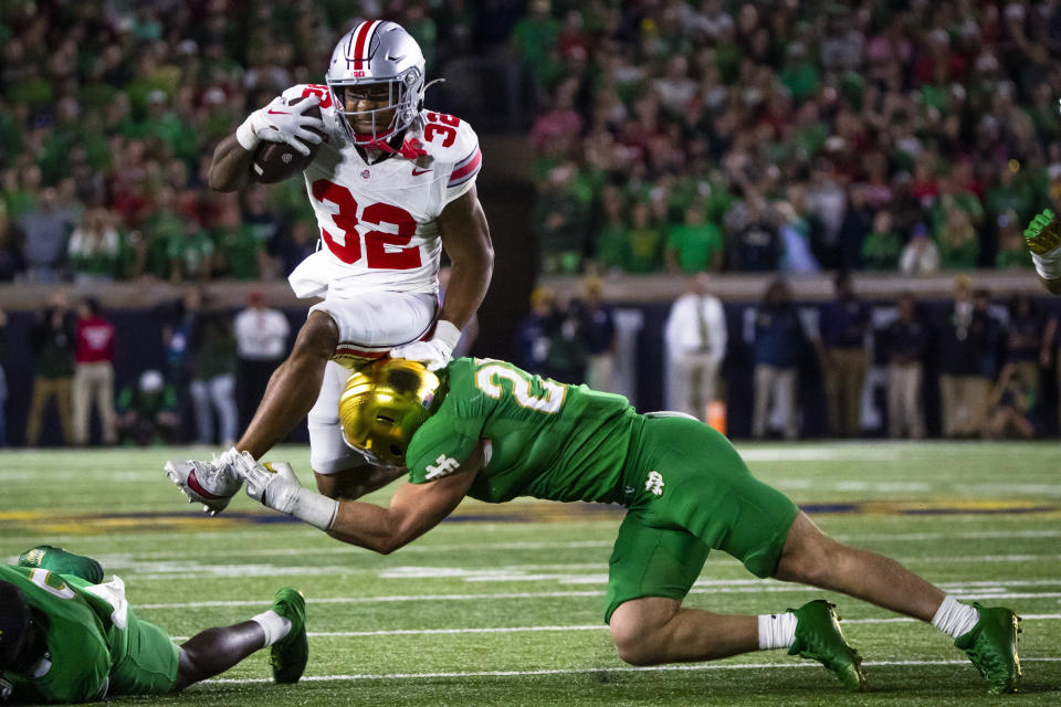Ohio State running back TreVeyon Henderson (32) tries to jump over Notre Dame linebacker JD Bertrand (27) during the second half of an NCAA college football game Saturday, Sept. 23, 2023, in South Bend, Ind. (AP Photo/Michael Caterina)