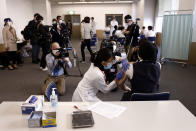 Members of the media watch a medical worker, right, receiving a dose of the COVID-19 vaccine at Tokyo Medical Center in Tokyo Wednesday, Feb. 17, 2021. Japan's first coronavirus shots were given to health workers Wednesday, beginning a vaccination campaign considered crucial to holding the already delayed Tokyo Olympics. (Behrouz Mehri/Pool Photo via AP)