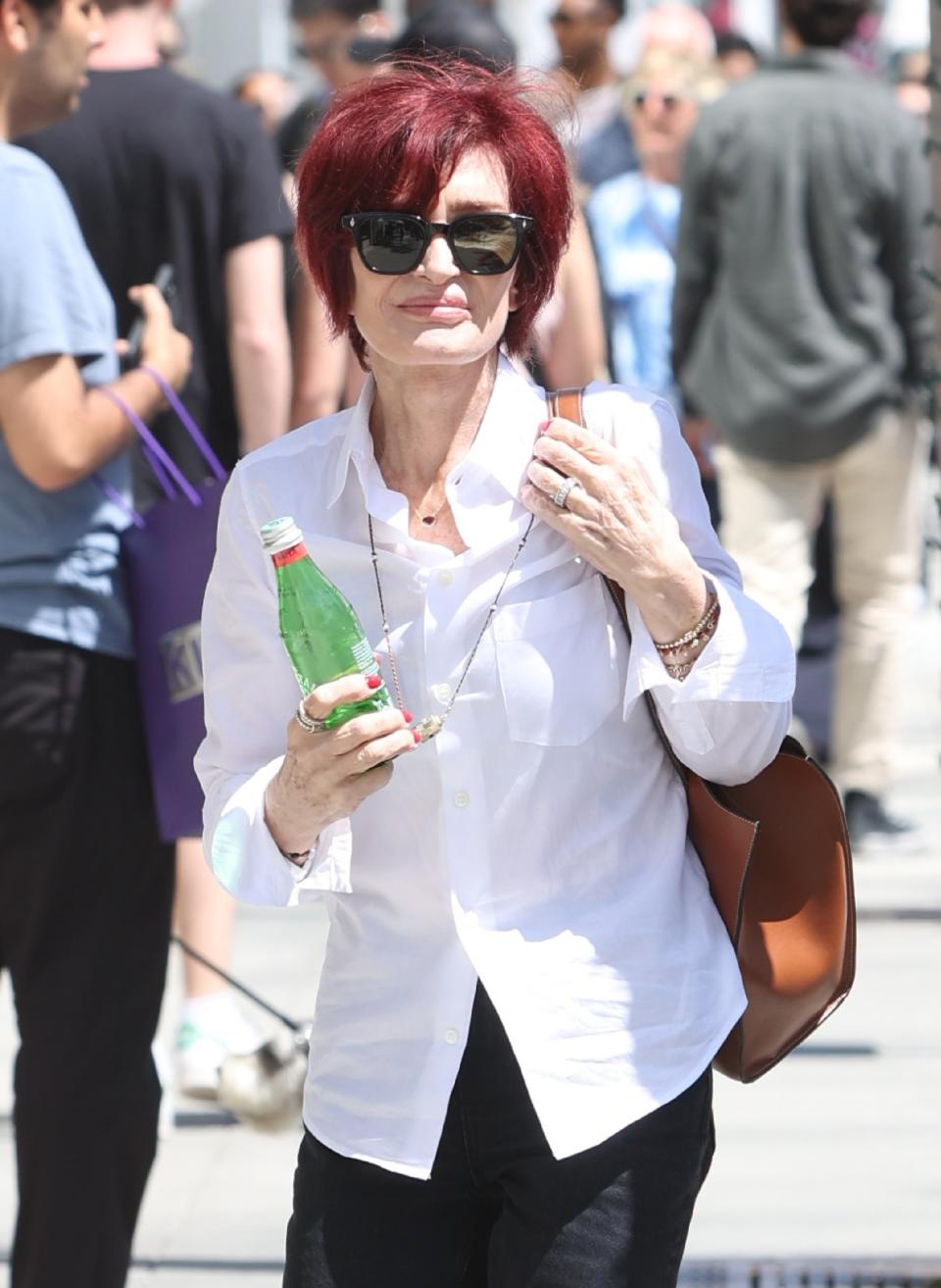 Closeup of Sharon Osbourne walking with a bottle of water