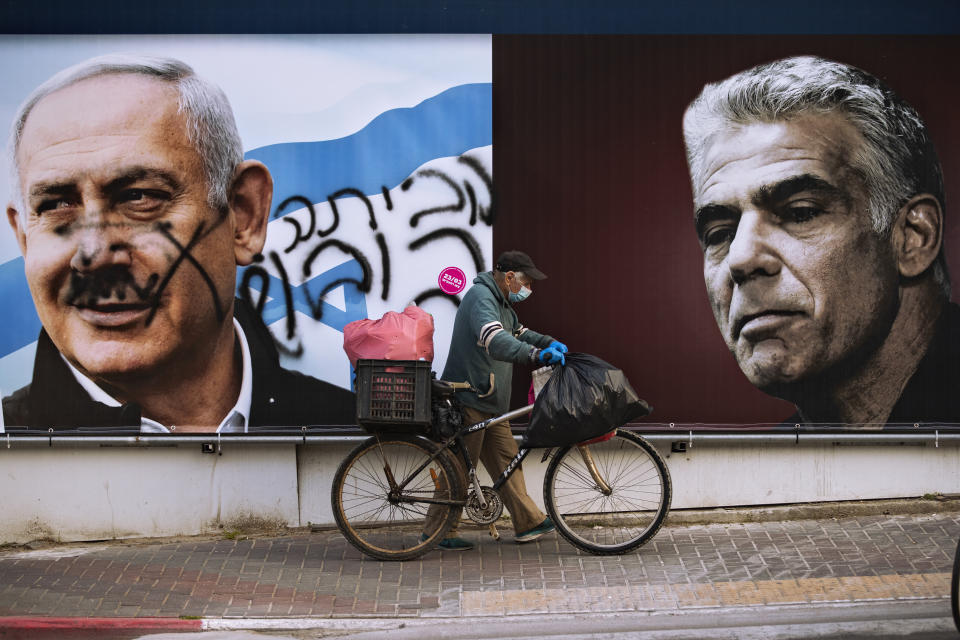 An election campaign billboard for the Likud party that shows a portrait of its leader Prime Minister Benjamin Netanyahu, left, and opposition party leader Yair Lapid, is defaced with Hebrew that reads, "go home," in Ramat Gan, Israel, Sunday, March 21, 2021. Israelis head to the polls on Tuesday for what will be the fourth parliamentary election in just two years. Once again, the race boils down to a referendum on Prime Minister Benjamin Netanyahu. (AP Photo/Oded Balilty)