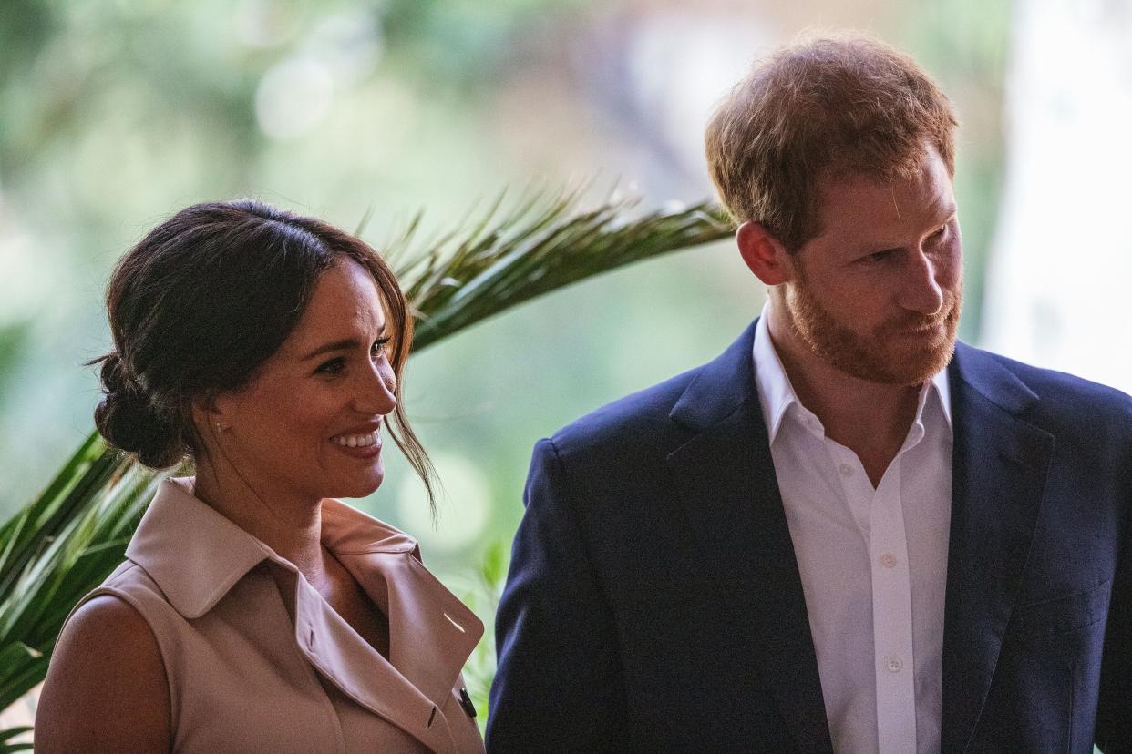 Britain's Prince Harry, Duke of Sussex(R) and Meghan, the Duchess of Sussex(L) stand on the stage at the British High Commissioner residency in Johannesburg where they  will meet with Graca Machel, widow of former South African president Nelson Mandela, in Johannesburg, on October 2, 2019. - Prince Harry recalled the hounding of his late mother Diana to denounce media treatment of his wife Meghan Markle, as the couple launched legal action against a British tabloid for invasion of privacy. (Photo by Michele Spatari / AFP) (Photo by MICHELE SPATARI/AFP via Getty Images)