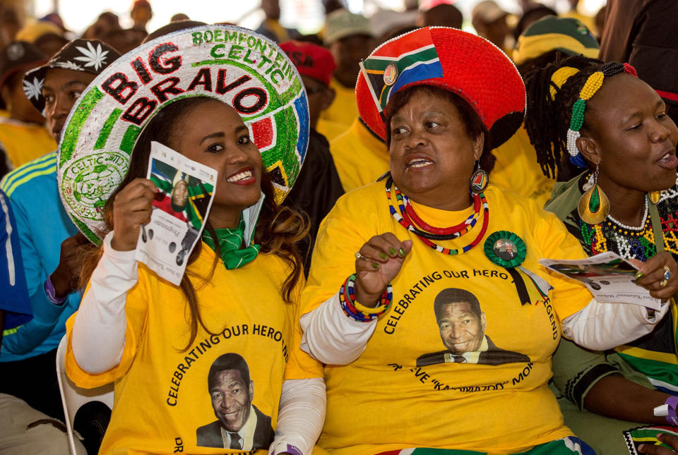 Mourners attend a memorial service for the late South African footballer, Steve "Kalamazoo" Mokone, portrait on tee shirts, at the FNB Soccer Stadium in Soweto, Johannesburg, Saturday, April 11, 2015. Mokone's remains arrived back in South Africa, Friday after he passed away in the USA last month. (AP Photo)