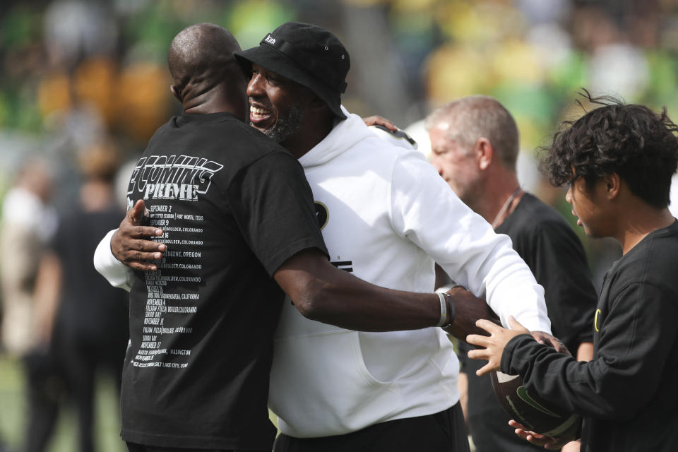 Terrell Owens, left, hugs Portland Trail Blazers head coach Chauncey Billups during warm ups before an NCAA football game between Colorado and Oregon, Saturday, Sept. 23, 2023, in Eugene, Ore. (AP Photo/Amanda Loman)