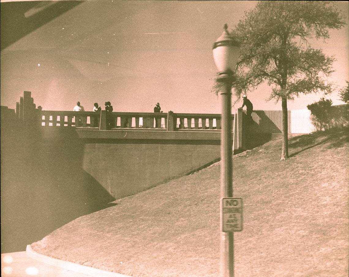 Nov. 22, 1963: Photo taken from moving press bus, people standing on the bridge overlooking grassy knoll after President John F. Kennedy’s assassination.