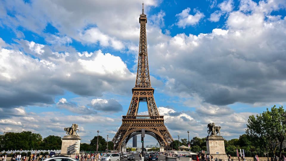 Cars drive past the Eiffel Tower in Paris on August 16, 2023. Americans have been flocking to Europe all summer. - Miguel Medina/AFP/Getty Images