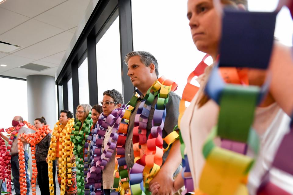 Community members hold hands as a paper chain hangs from their necks, serving as a petition, during a Greenville County Council public forum at Greenville County Square on Tuesday, Sept. 12, 2023. Community advocates delivered a petition calling to have the chairman removed from the library board.