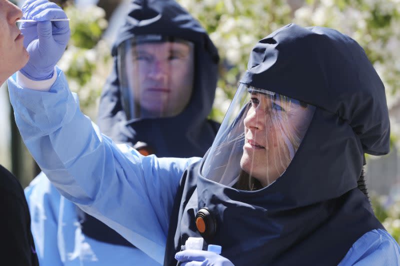 Salt Lake County infectious disease nurse Travis Langston looks on as public health nurse Lee Cherie Booth conducts a test for COVID-19 before contact tracing takes place. (AP)