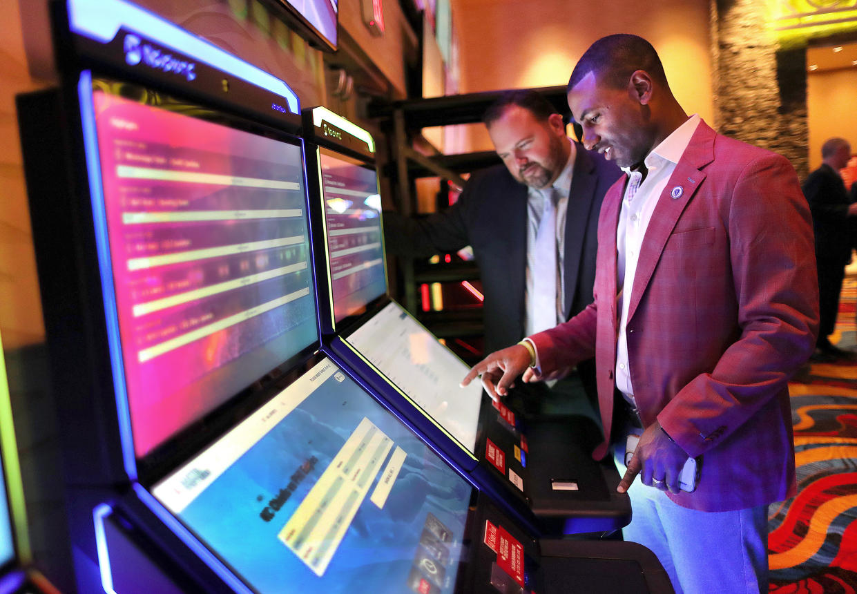 Massachusetts State Rep. Marcus Vaughn places a bet at a kiosk as fellow State Rep. David Muradian looks on during the first day of in-person sports betting in Massachusetts. (Photo by John Tlumacki/The Boston Globe via Getty Images)