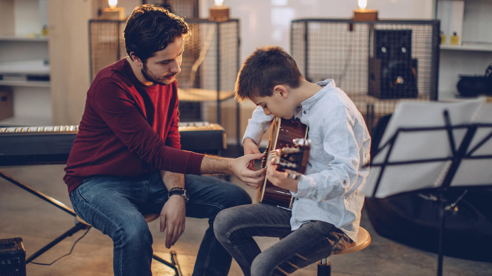 Man shows a child how to play the acoustic guitar