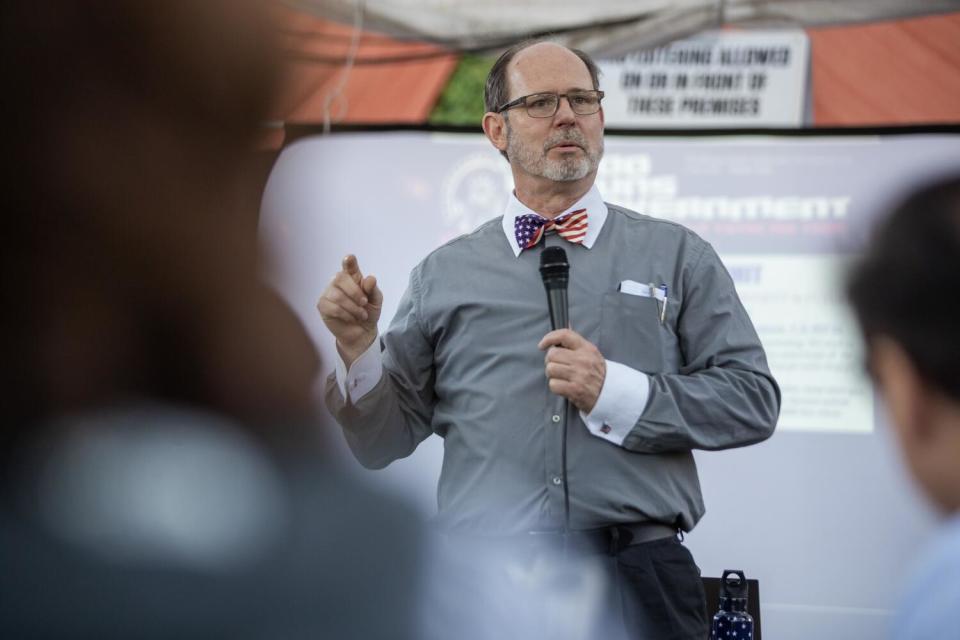 A man with a microphone speaks at a gathering