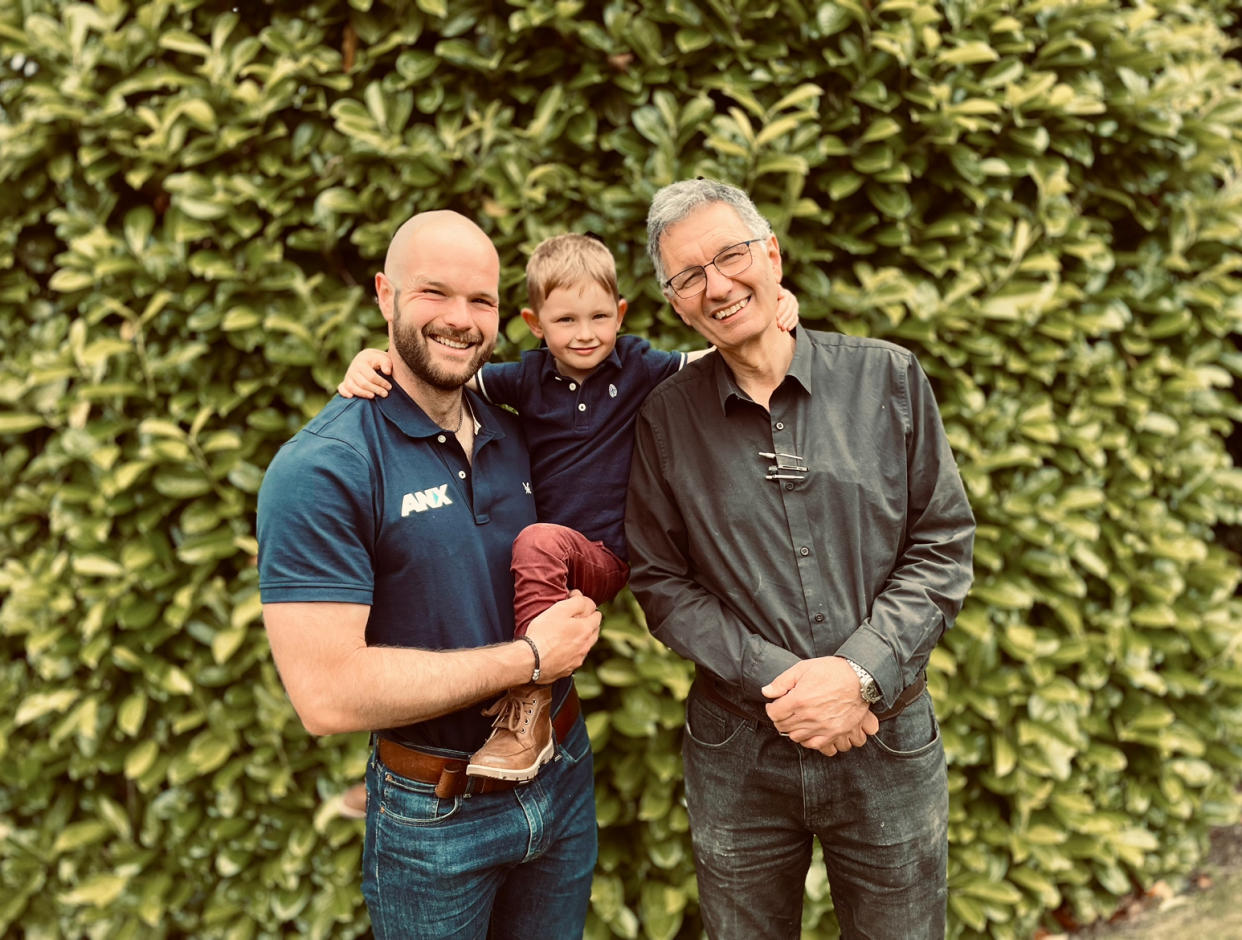 Two men holding boy and standing and posing for a photo