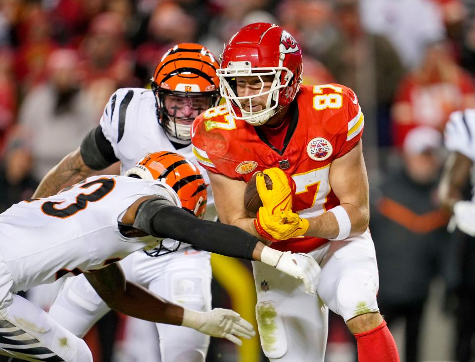 Kansas City Chiefs tight end Travis Kelce (87) runs with the ball against Cincinnati Bengals safety Dax Hill (23) and linebacker Logan Wilson (55) during the second half at GEHA Field at Arrowhead Stadium.