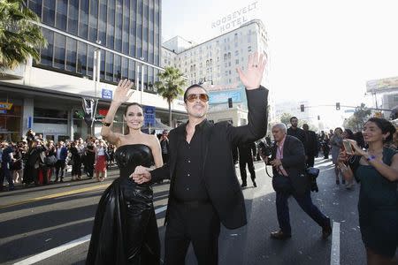 Cast member Angelina Jolie and actor Brad Pitt wave at fans as they arrive at the premiere of "Maleficent" at El Capitan theatre in Hollywood, California May 28, 2014. REUTERS/Mario Anzuoni