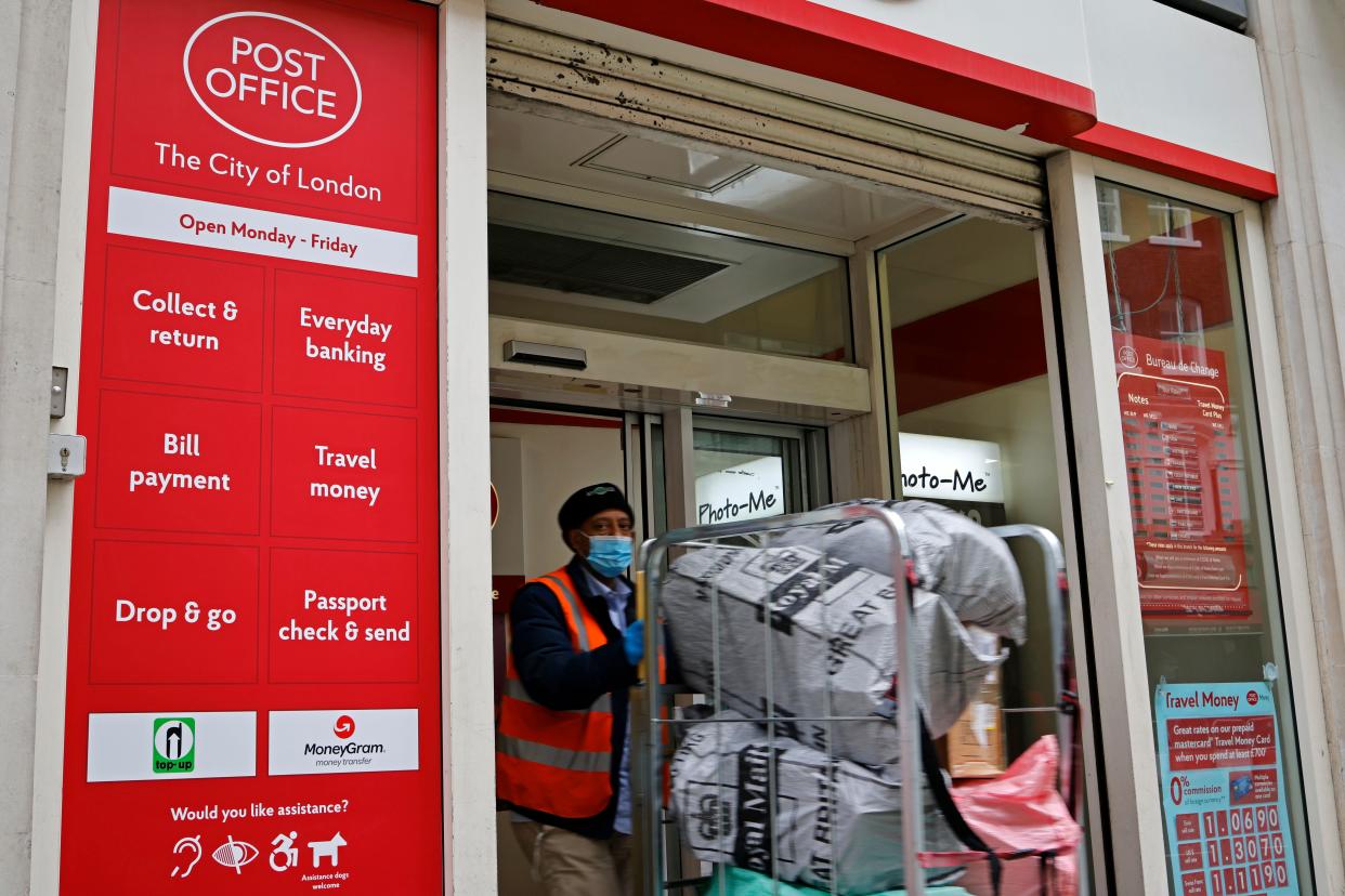 A Royal Mail worker wearing a protective face covering to combat the spread of the coronavirus, leaves a Post Office in the City of London with a trolly of packages on December 29, 2020, as UK businesses and individuals learn to follow new rules after the UK leaves the European Union. - New rules come into force over the sending of parcels to the EU (European Union) in a post-Brexit world. Any parcel being sent from England, Scotland or Wales to an EU country should have a customs declaration form attached to it from today, December 29. (Photo by Tolga Akmen / AFP) (Photo by TOLGA AKMEN/AFP via Getty Images)