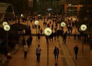 People walk through Canary Wharf while the sky overhead turns red as dust from the Sahara carried by storm Ophelia filters sunlight over London. REUTERS/Tom Jacobs