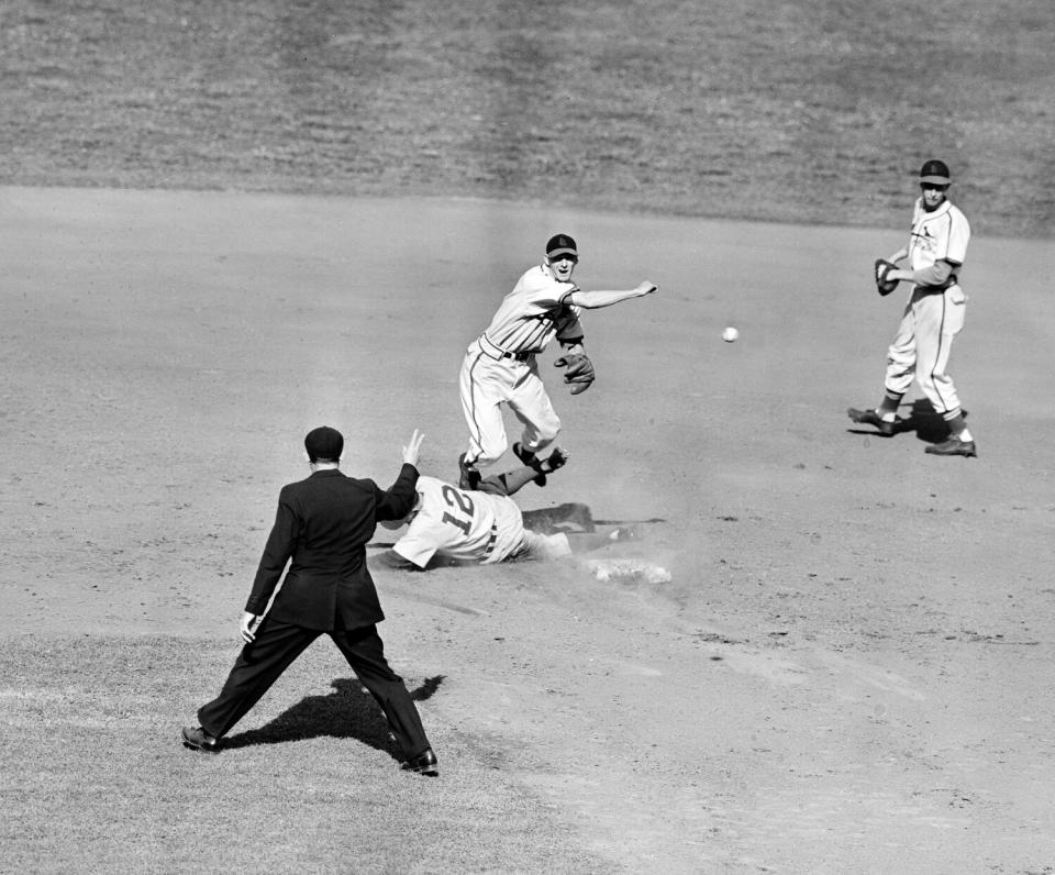 St. Louis Cardinals shortstop Marty Marion leaps high to avoid the spikes of sliding Brooklyn runner Ed Stanky.