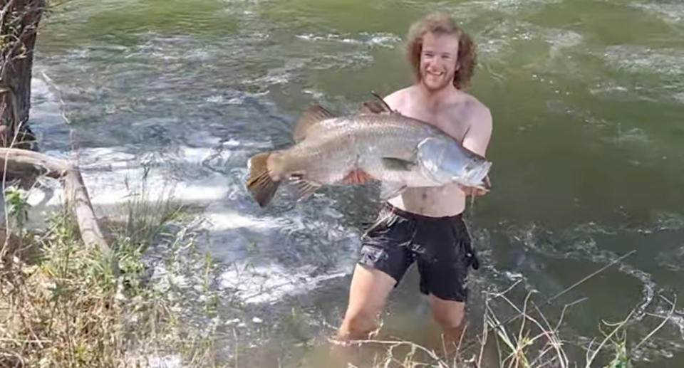 Fisherman holding barramundi fish caught in Tianroo Dam