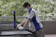 In this Wednesday, June 3, 2020 photo, an employee at Universal Orlando Resort sprays sanitizer as he wipes down a hand rail on a people mover, Wednesday, June 3, 2020, in Orlando, Fla. The theme park has reopened for season pass holders and will open to the general public on Friday, June 5. (AP Photo/John Raoux)