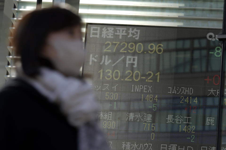 A person wearing a protective mask walks in front of an electronic stock board showing Japan's Nikkei 225 index at a securities firm Wednesday, Jan. 25, 2023, in Tokyo. Asian shares were mixed Wednesday after Wall Street indexes finished little changed as investors awaited earnings results from major global companies. (AP Photo/Eugene Hoshiko)