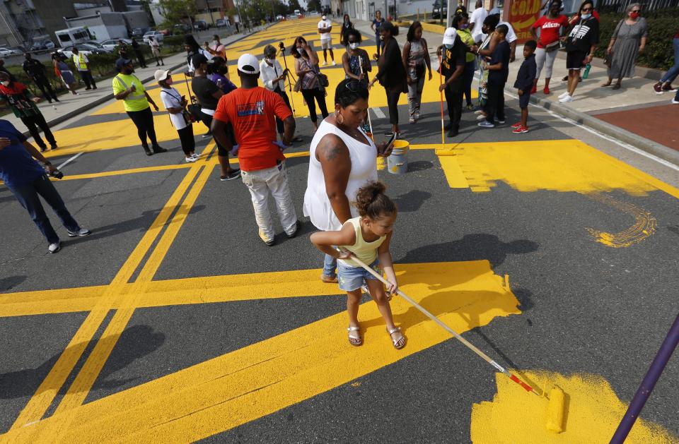 FILE - In this Sept. 4, 2020 file photo, Kenya Fulk applies paint to a Black Lives Matter mural on Martin Luther King Jr. Boulevard during a Black Lives Matter event, in Atlantic City, N.J. Atlantic City says it will re-do the Black Lives Matter tribute because the original painting of those words across the entire street confused motorists who didn't know where to drive on it. (AP Photo/Noah K. Murray, File)