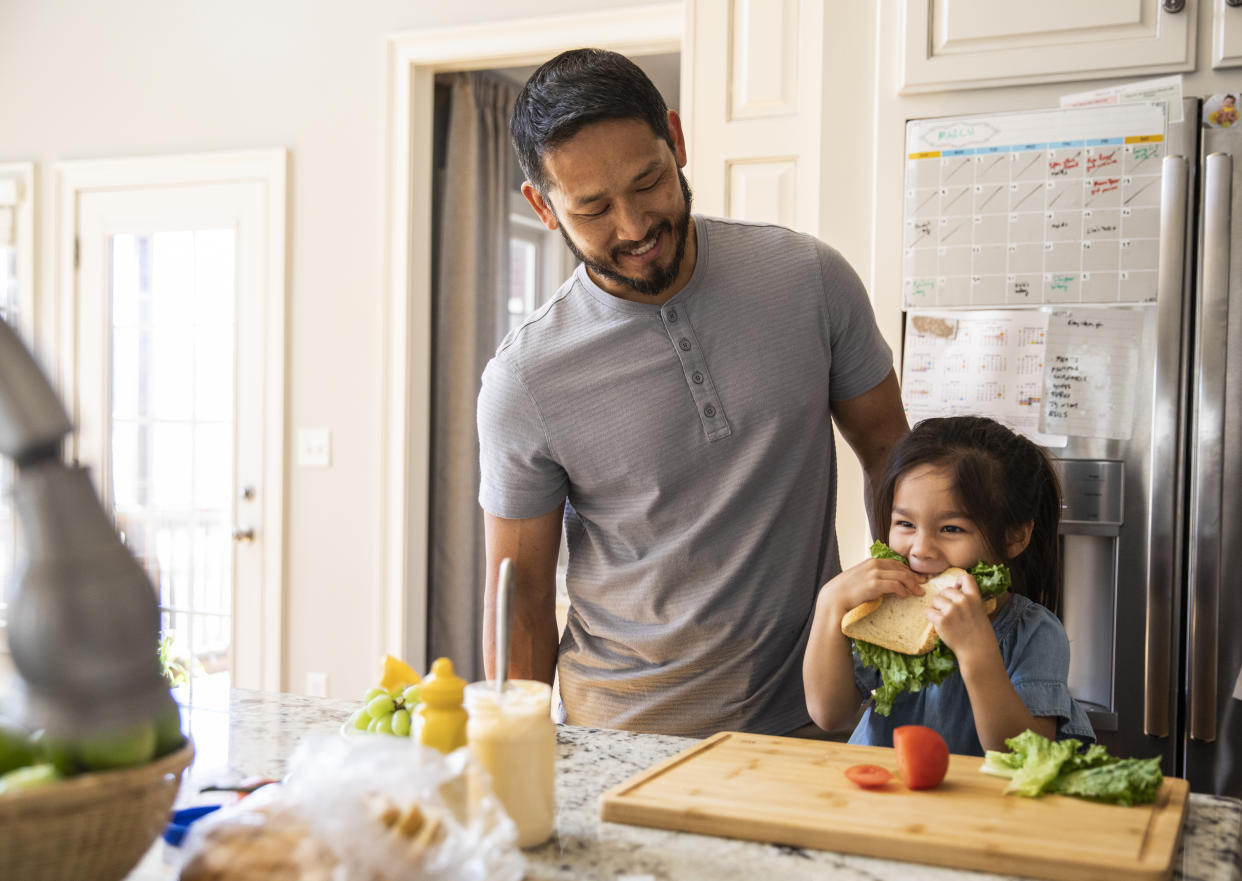 Father and daughter making sandwich in kitchen