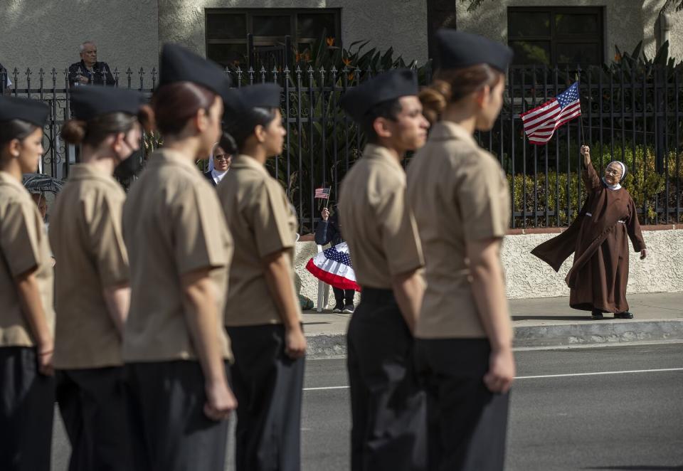 A nun holds an American flag on a street during a parade