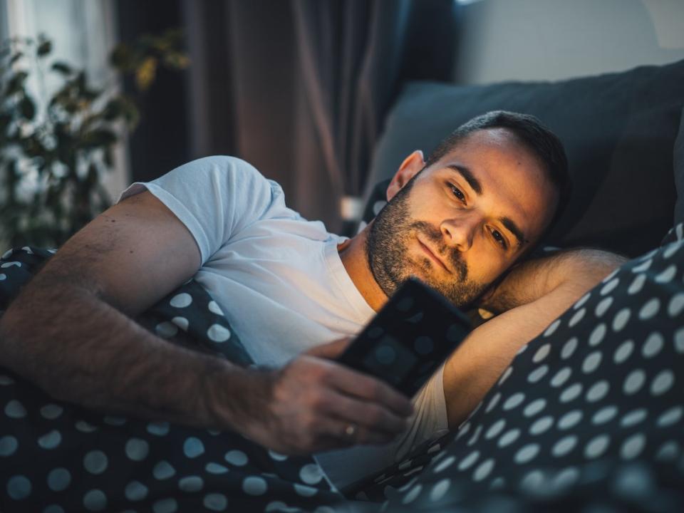 man using phone in bed