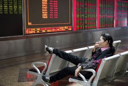 An investor rests on a chair in front of an electronic board showing stock information at a brokerage house in Beijing, China, October 13, 2015. REUTERS/Stringer CHINA OUT