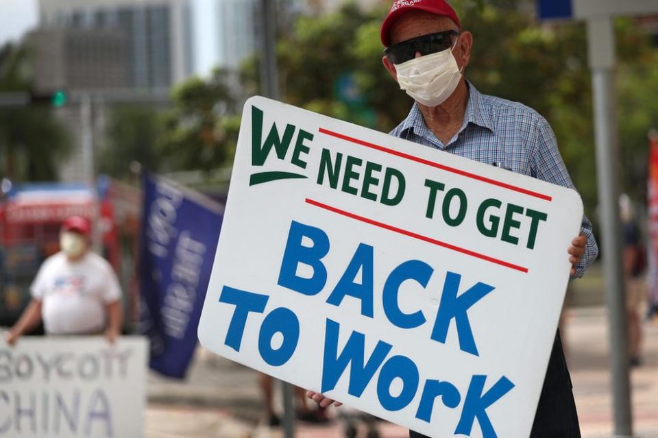 Hombre con cartel pidiendo la vuelta al trabajo.