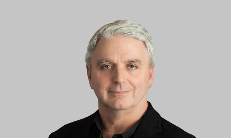 Unity Technologies CEO John Riccitiello. Portrait (facing camera) in front of a gray background.