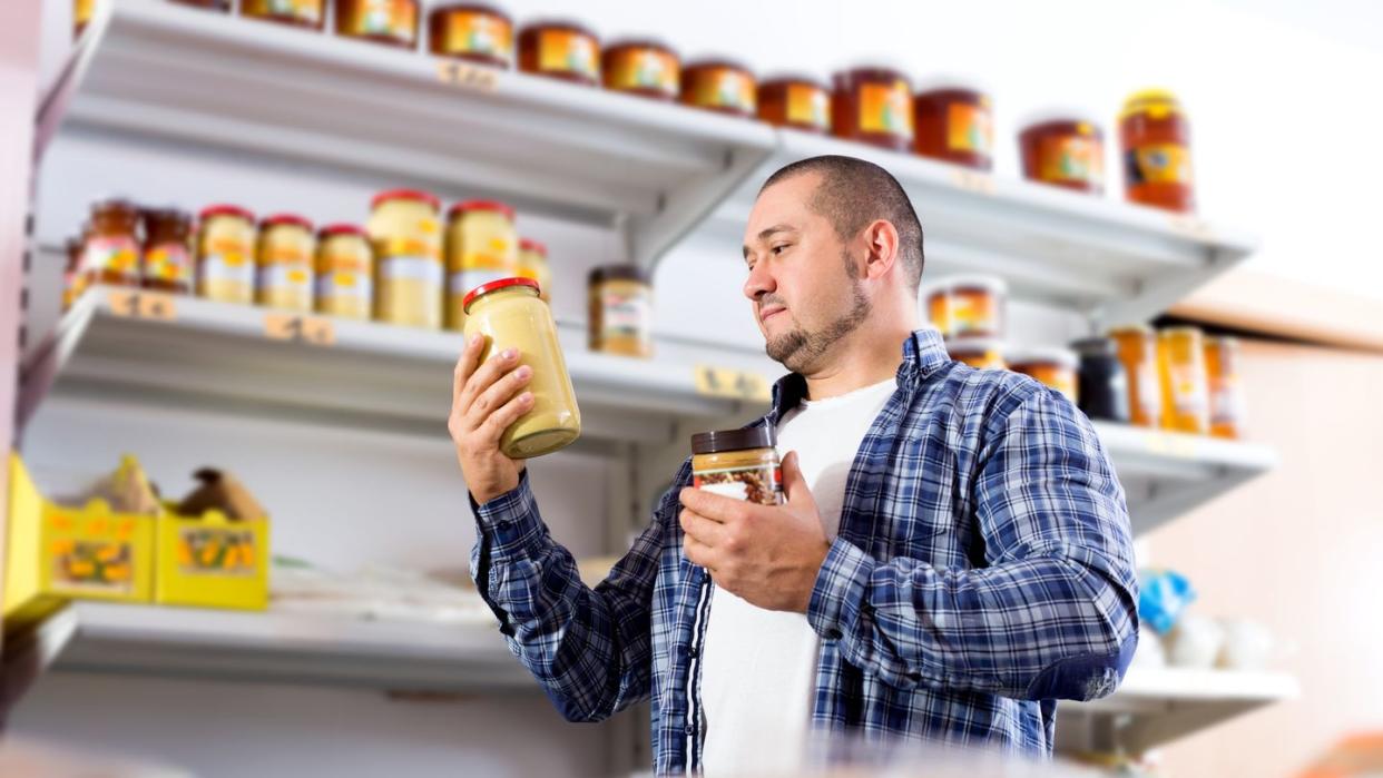 portrait of ordinary man purchasing peanut butter in grocery