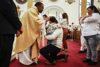 Father Ako Walker gives communion during Easter Mass at Sacred Heart of Jesus and Saint Patrick, Sunday, March 31, 2024, in Baltimore, Md. (AP Photo/Julia Nikhinson)