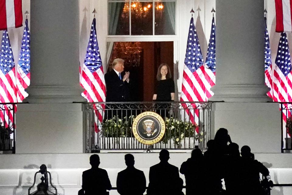 President Donald Trump applauds Amy Coney Barrett as they stand on the Blue Room Balcony after Supreme Court Justice Clarence Thomas administered her the Constitutional Oath on the South Lawn of the White House in Washington, Monday, Oct. 26, 2020.