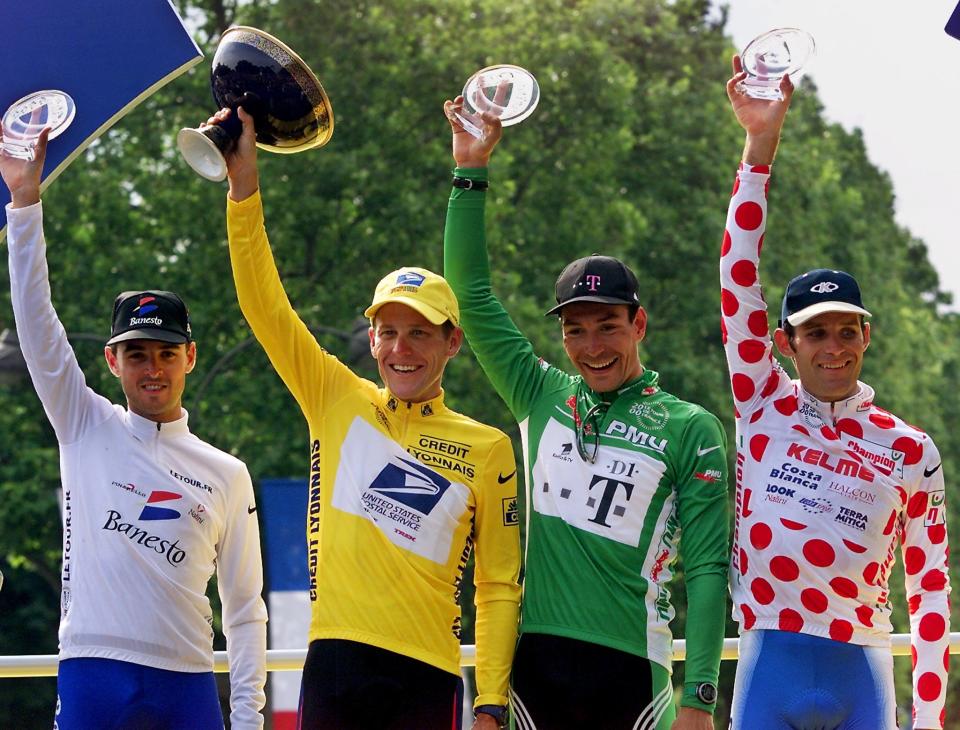 The 2000 Tour de France winner US Lance Armstrong celebrates on the podium with the green jersey of best sprinter German Erik Zabel, the polka-dot jersey of best climber Colombian Santiago Botero (R) and the white jersey of best young rider Spanish Francisco Mancebo (L) on the podium on the 'Champs Elysees' after the last stage in Paris 23 July 2000.  AFP PHOTO PATRICK KOVARIK  (Photo credit should read PATRICK KOVARIK/AFP/GettyImages)