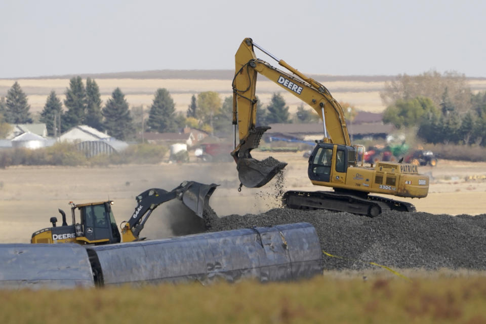 Heavy equipment moves gravel Sunday, Sept. 26, 2021, next to cars from an Amtrak train that derailed the day before just west of Joplin, Mont., killing three people and injuring others. The westbound Empire Builder was en route to Seattle from Chicago, with two locomotives and 10 cars. (AP Photo/Ted S. Warren)