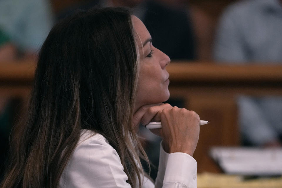 Karen Read watches as her legal team meets at the side bar during Read's trial in Norfolk Superior Court, Friday, June 14, 2024, in Dedham, Mass. Read, 44, is accused of running into her Boston police officer boyfriend with her SUV in the middle of a nor'easter and leaving him for dead after a night of heavy drinking. (AP Photo/Charles Krupa, Pool)