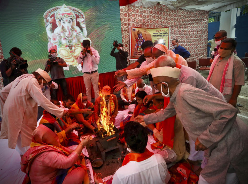 Hindus offer prayers for a groundbreaking ceremony of a temple dedicated to the Hindu god Ram in Ayodhya, at the Vishwa Hindu Parishad, or World Hindu Council, headquarters in New Delhi, India, Wednesday, Aug. 5, 2020. The coronavirus is restricting a large crowd, but Hindus were joyful before Prime Minister Narendra Modi breaks ground Wednesday on a long-awaited temple of their most revered god Ram at the site of a demolished 16th century mosque in northern India. (AP Photo/Manish Swarup)