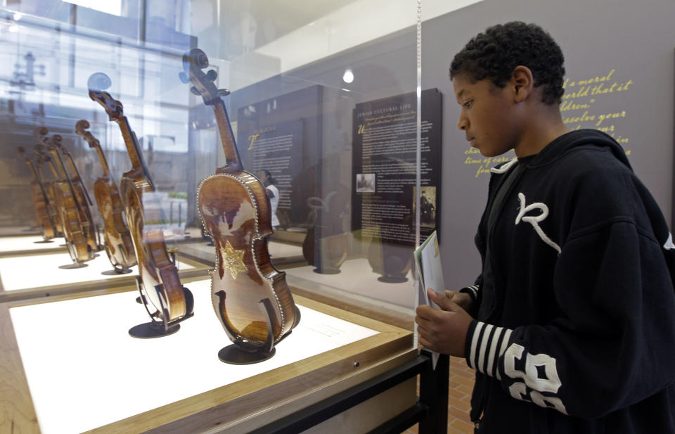 In a Monday, April 9, 2012 photo, Lorryan Smith, 12, looks at violins on display at the Violins of Hope exhibit at UNC Charlotte in Charlotte, N.C. Eighteen violins recovered from the Holocaust and restored by Israeli violin maker Amnon Weinsten make their U.S. debut on Sunday, April 15. Some were played by Jewish prisoners in Nazi concentration camps, while others belonged to the Jewish Klezmer musical culture. (AP Photo/Chuck Burton)