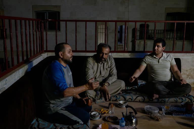 Aziz al-Asmar, izquierda, con amigos compartiendo mate en su casa en Binnish, Siria