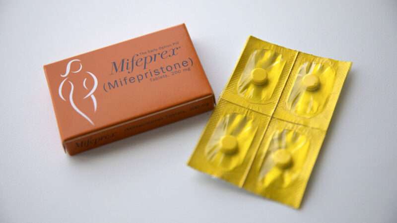 Mifepristone pills next to their box against a gray background