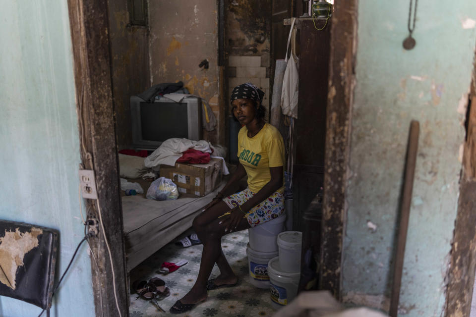 Anet Ayala se sienta en un balde junto a su cama en su casa, el segundo piso de un antiguo edificio donde vive con su hermano en el barrio Talla Piedra de La Habana, Cuba, el lunes 13 de junio de 2022. (AP Foto/Ramón Espinosa)