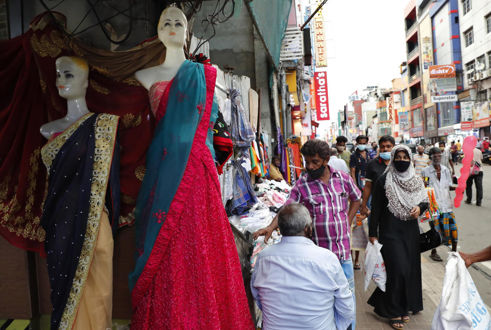 A Sri Lankan Muslim woman, right in black attire, walks in a busy street of Colombo, Sri Lanka, Saturday, March 13, 2021. Sri Lanka on Saturday announced plans to ban the wearing of burqas and said it would close more than 1,000 Islamic schools known as madrassas, citing national security. ​(AP Photo/Eranga Jayawardena)