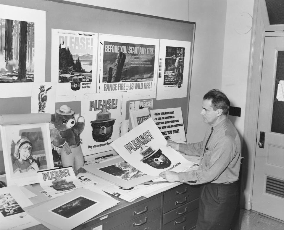 A park ranger in an office with a plethora of posters about preventing forest fires, most of which feature Smokey the Bear.  (Photo: Corbis via Getty Images)